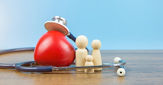 photo of stethoscope around a toy heart and wooden people